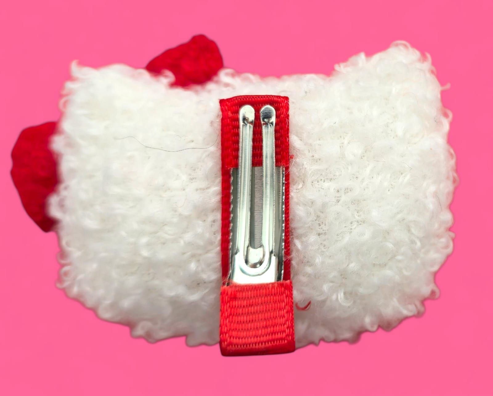 Peluche de Hello Kitty con forma de sushi, con lazo rojo, ojos negros, bigotes y pico amarillo, sobre fondo rosa.