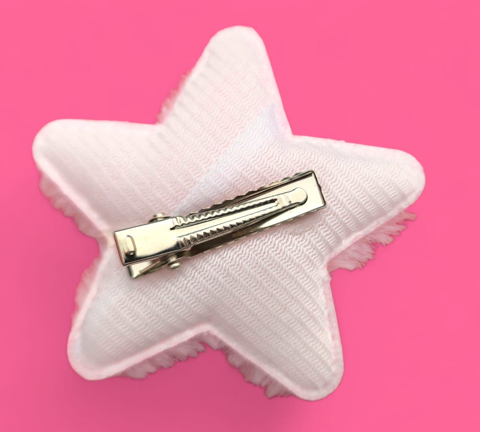 Peluche rosa en forma de estrella con la cara de Hello Kitty sobre fondo rosa.