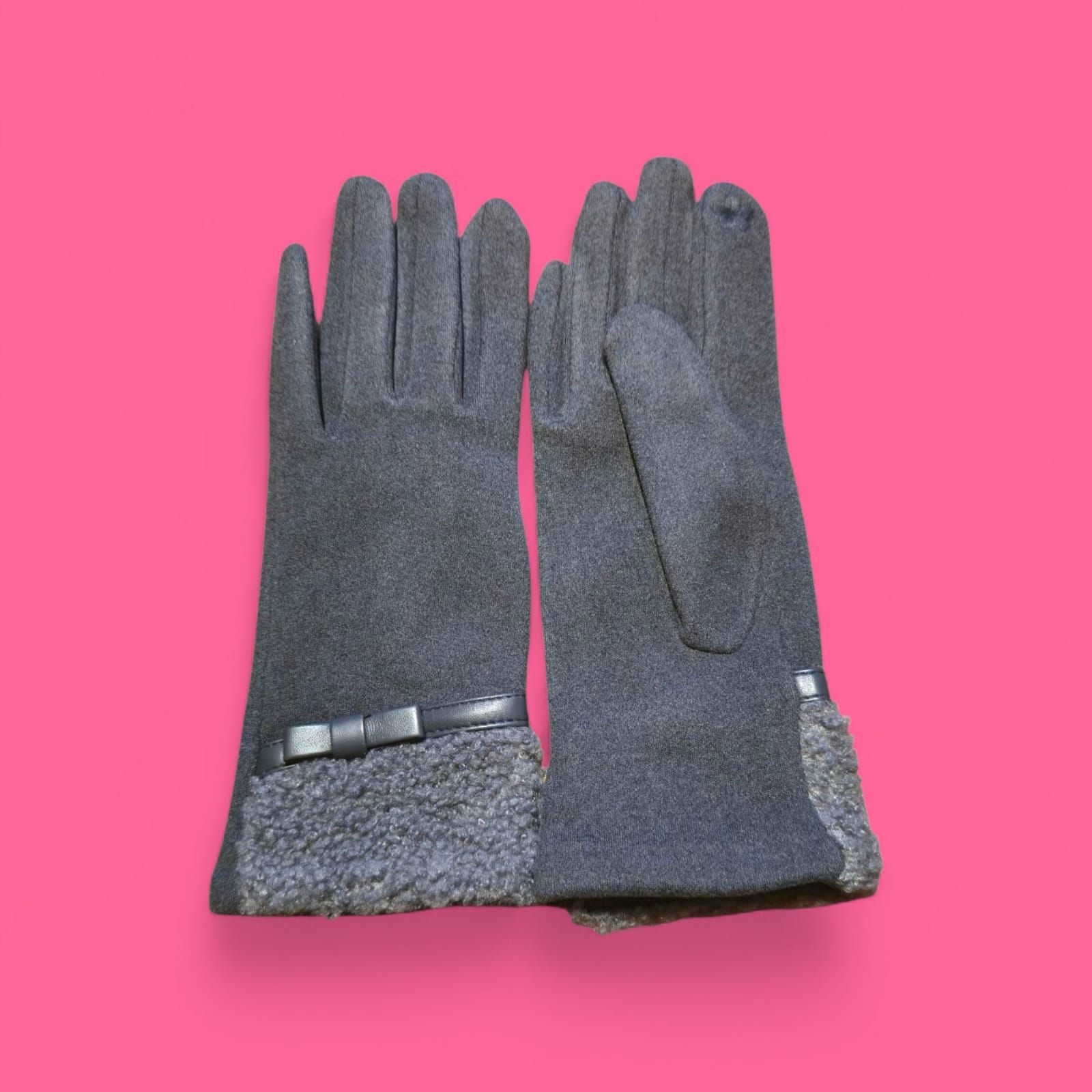 Guantes gris oscuro con puños texturizados y detalle de lazo sobre fondo rosa.