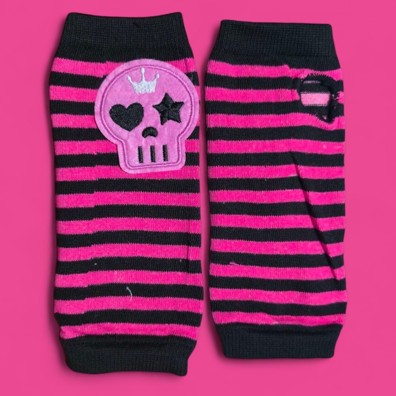 Par de calentadores de brazos a rayas negras y rosas, uno de ellos con un parche de calavera.