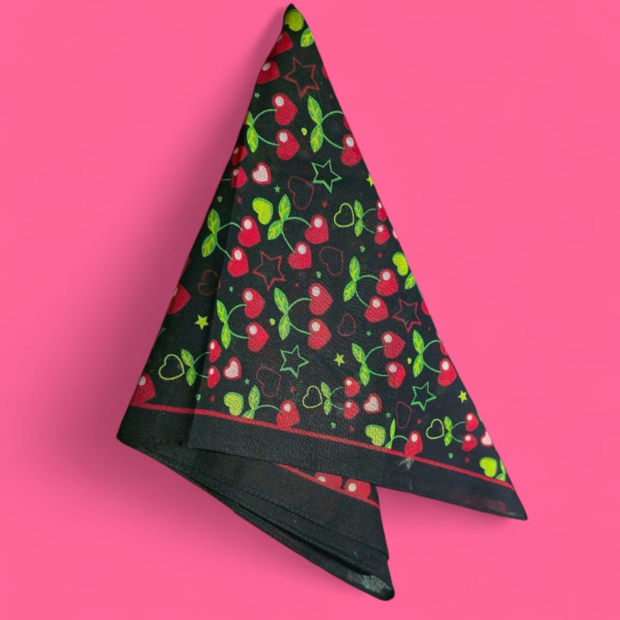 Pañuelo negro con cerezas rojas, corazones y estrellas sobre fondo rosa.