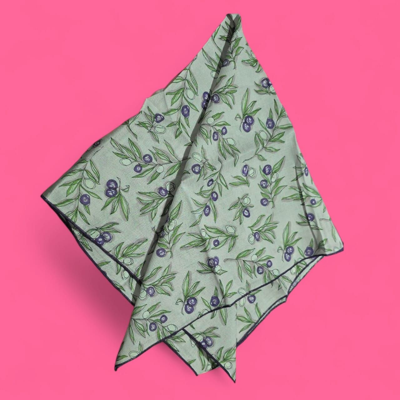 Pañuelo verde claro con estampado de ramas de olivo sobre fondo rosa.
