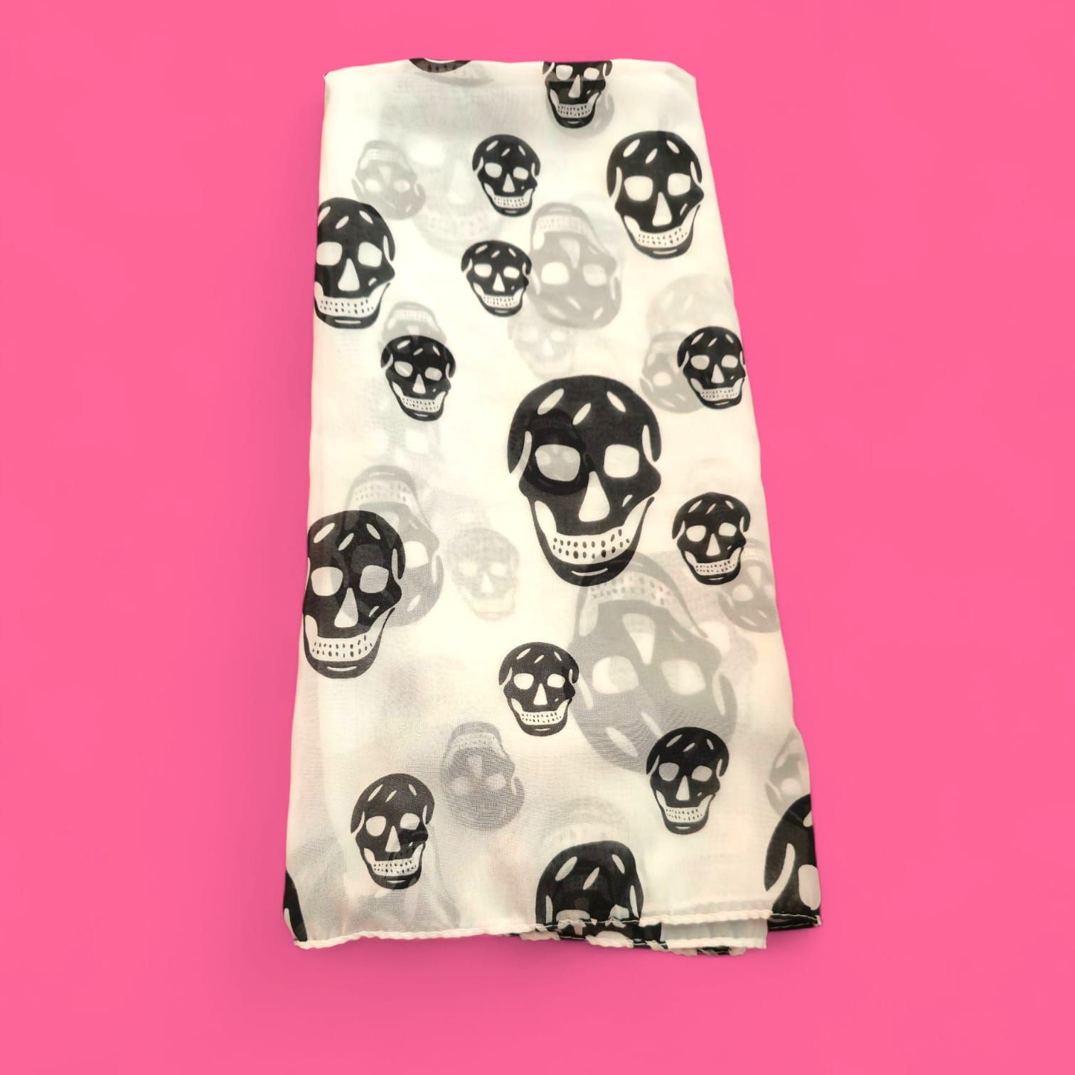 Bufanda blanca con estampado de calavera negra sobre fondo rosa.