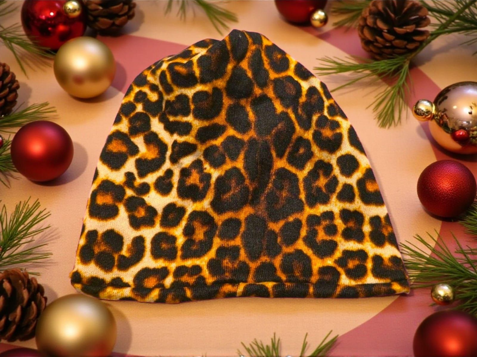 Gorro con estampado de leopardo en un ambiente festivo navideño con adornos y agujas de pino.