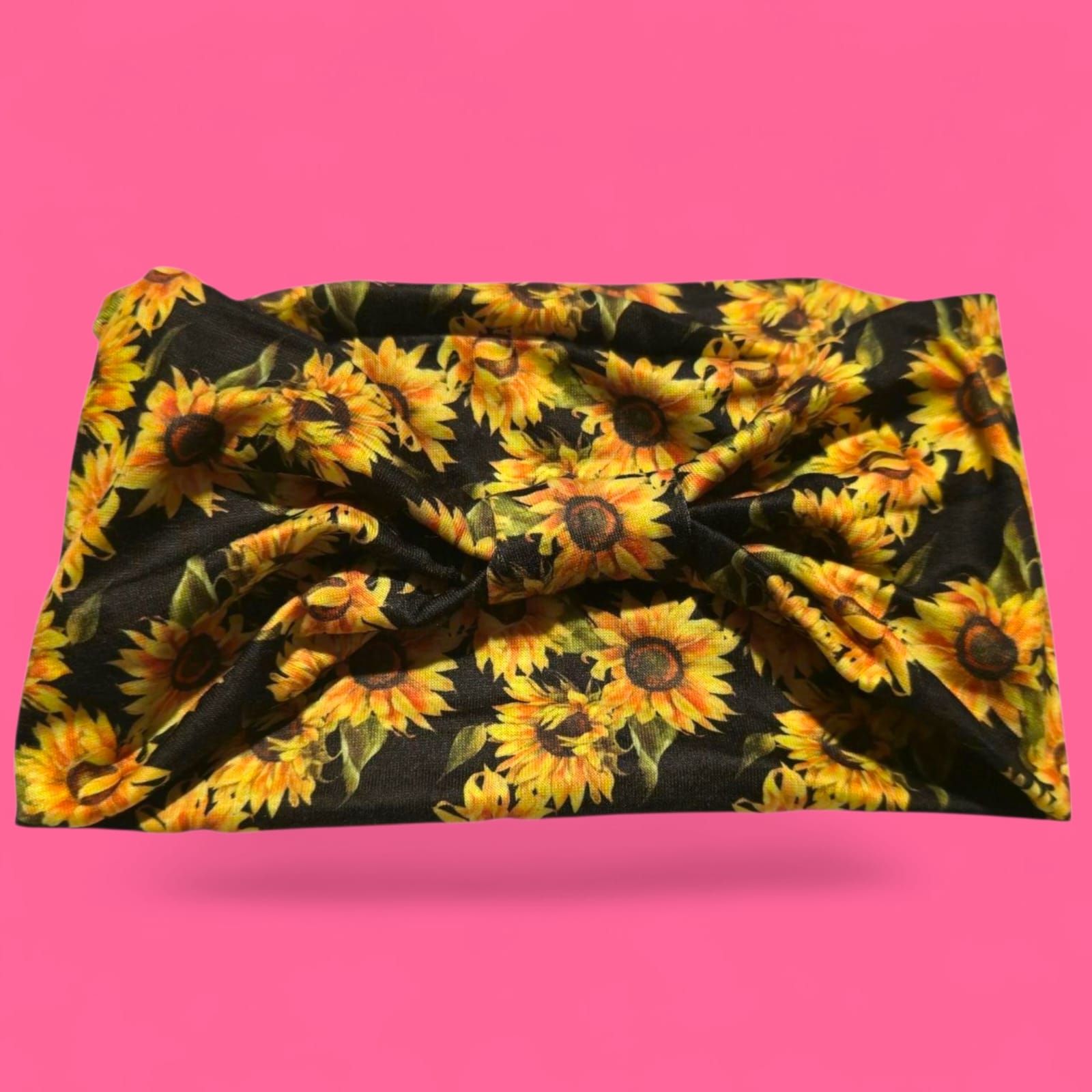 Tela negra con girasoles amarillos sobre fondo rosa brillante.