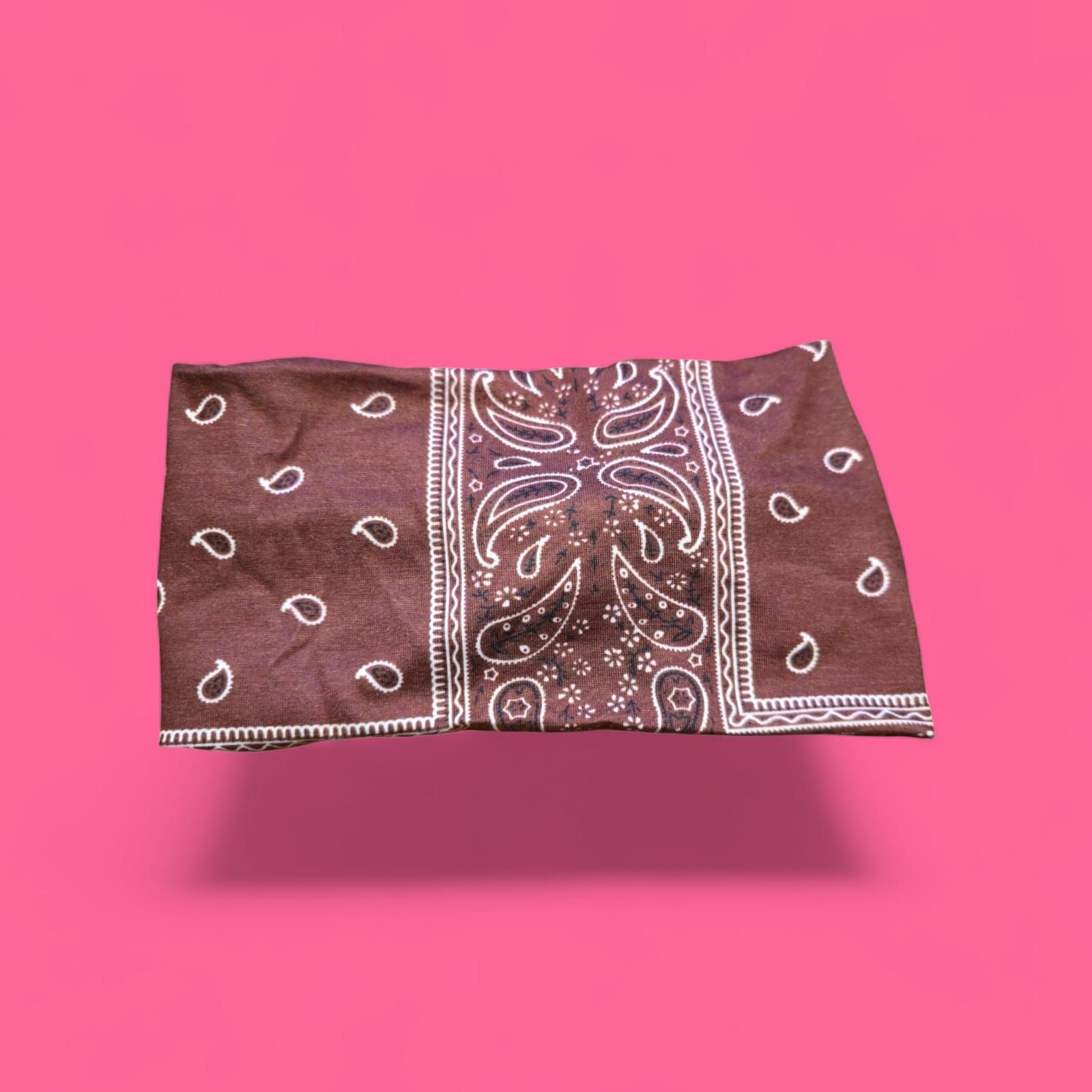 Pañuelo paisley marrón y blanco sobre fondo rosa.