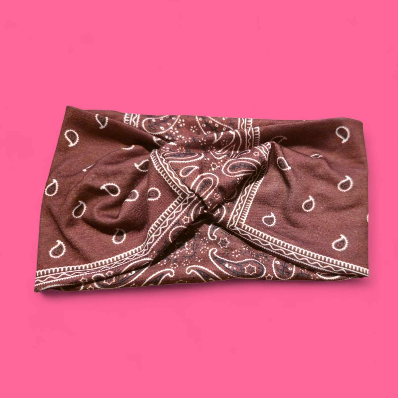 Pañuelo paisley marrón y blanco sobre fondo rosa.