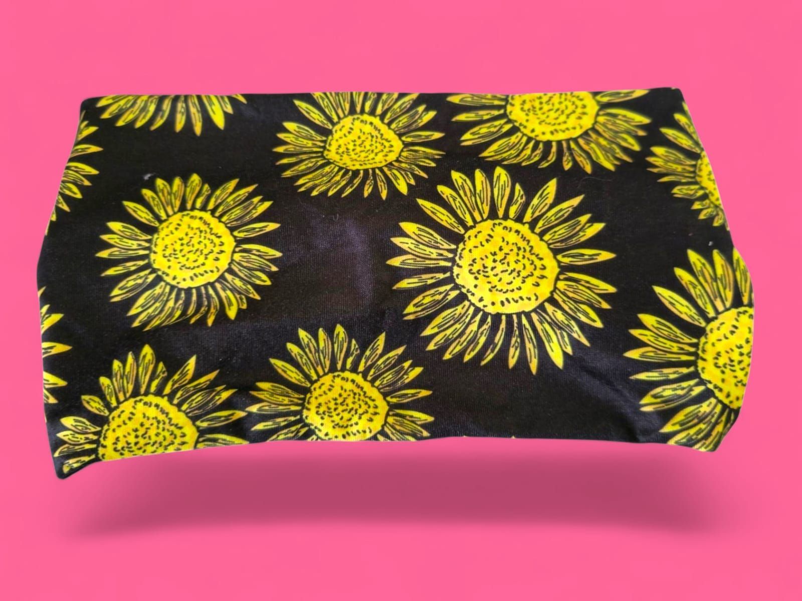 Tela negra con girasoles amarillos sobre fondo rosa.