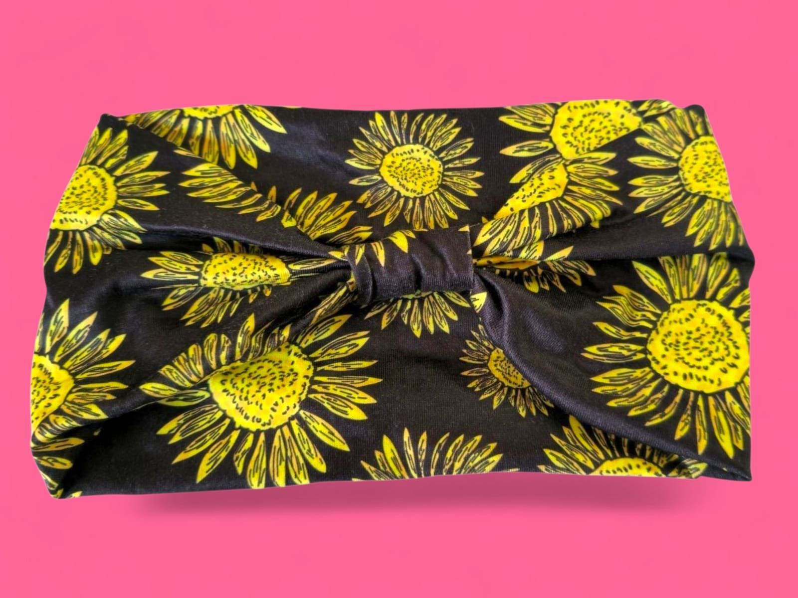 Tela negra con girasoles amarillos sobre fondo rosa.