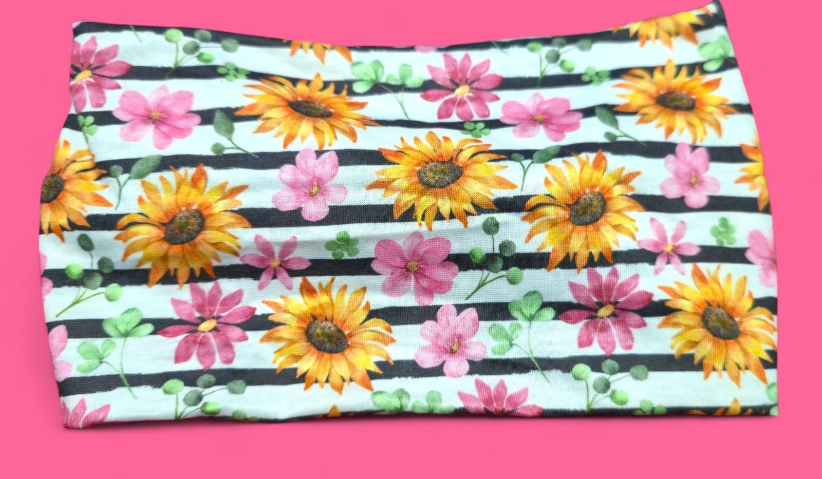 Diadema con girasoles, flores rosas, hojas verdes y estampado de rayas negras.
