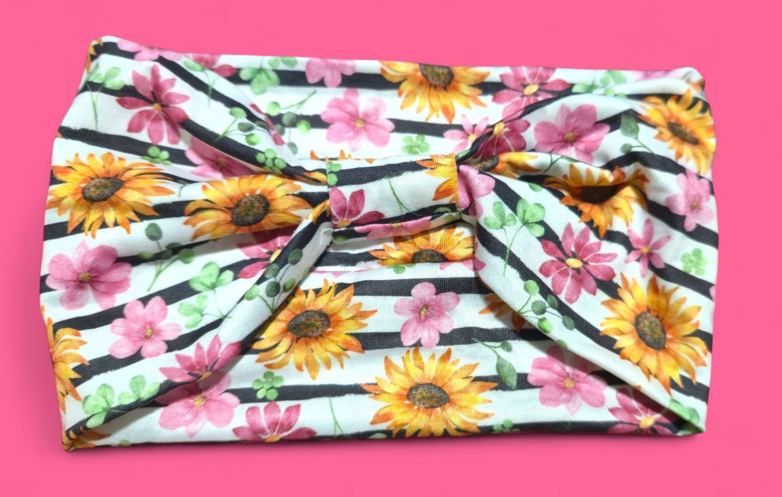 Diadema con girasoles, flores rosas, hojas verdes y estampado de rayas negras.