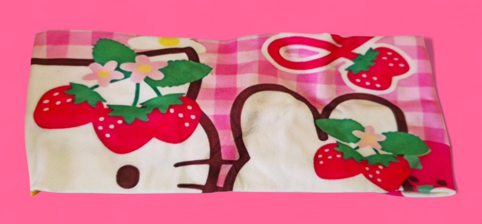 Toalla de Hello Kitty con fresas sobre fondo de cuadros vichy rosas.