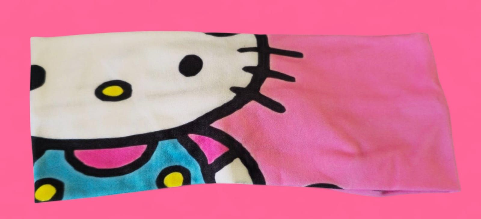 Diadema con diseño de Hello Kitty, con cara blanca, lazo rosa y detalles verde azulado.