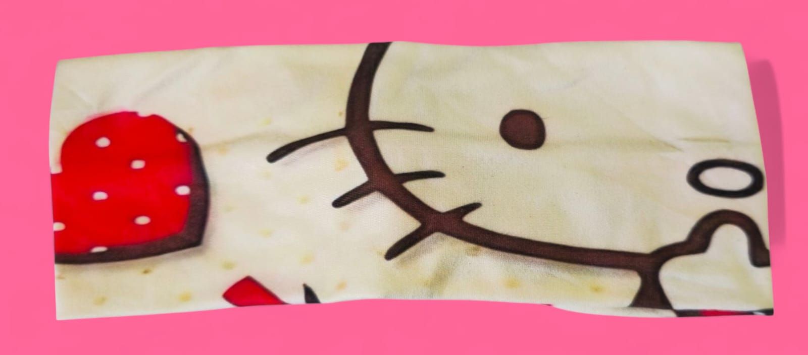 Almohada con temática de Hello Kitty con corazón rojo sobre fondo rosa.