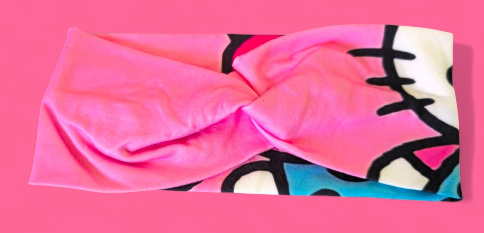 Diadema con diseño de Hello Kitty, con cara blanca, lazo rosa y detalles verde azulado.