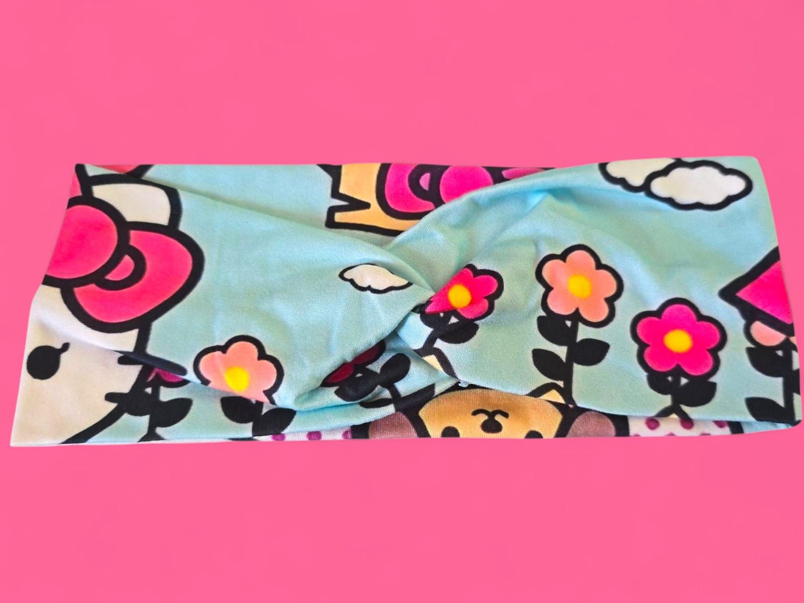 Toalla de Hello Kitty, color rosa y azul claro, con dibujo de perro y lunares, sobre fondo rosa.