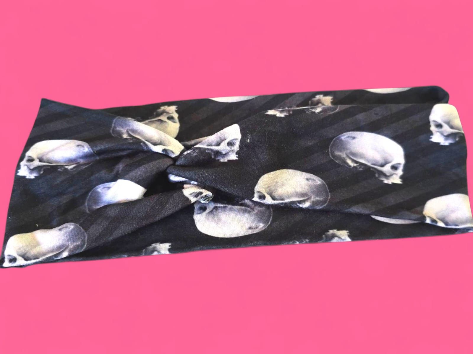 Corbata negra con estampado de calavera y rayas grises sobre fondo rosa.