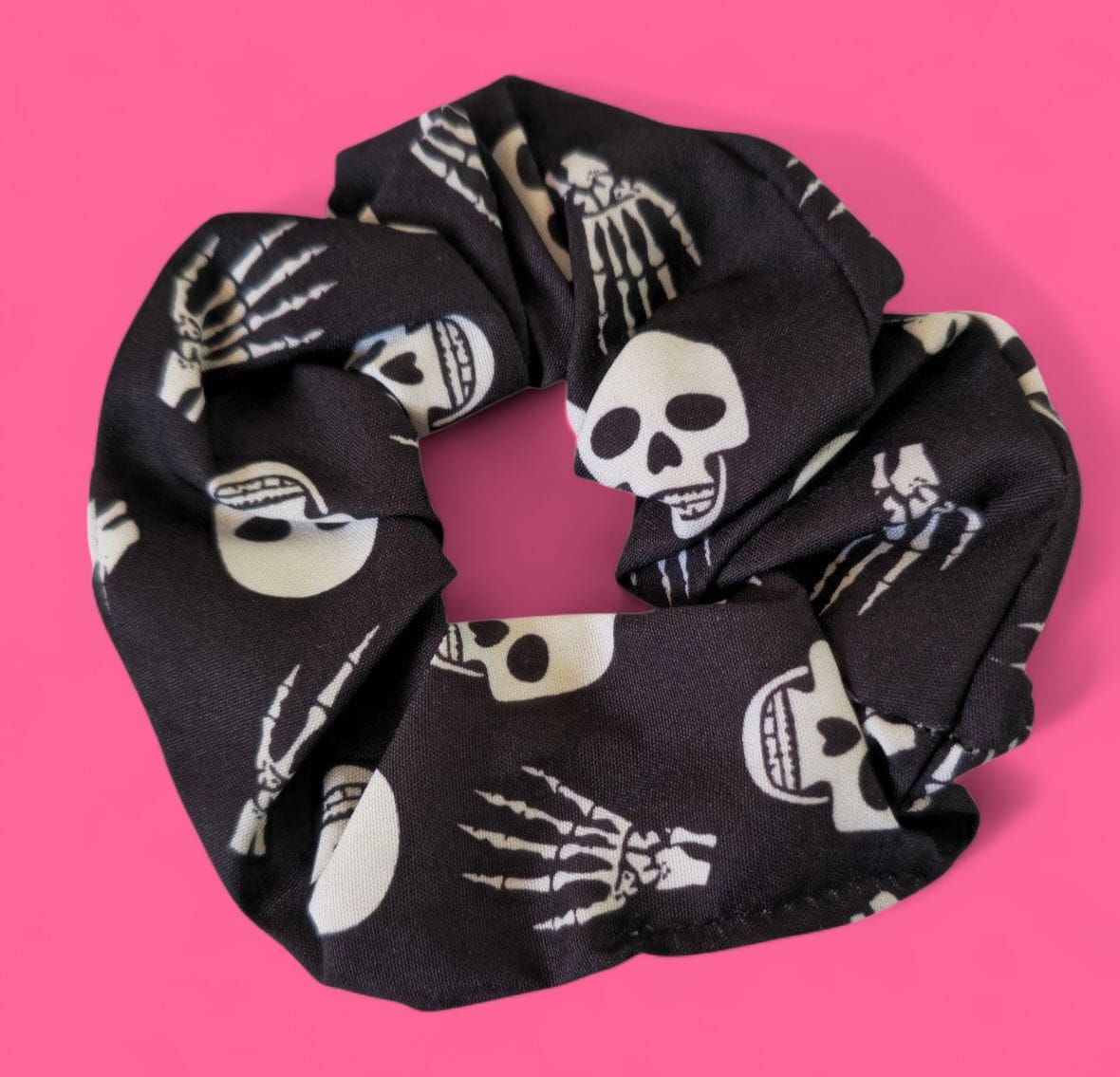 Coletero negro con estampado de esqueleto blanco sobre fondo rosa.