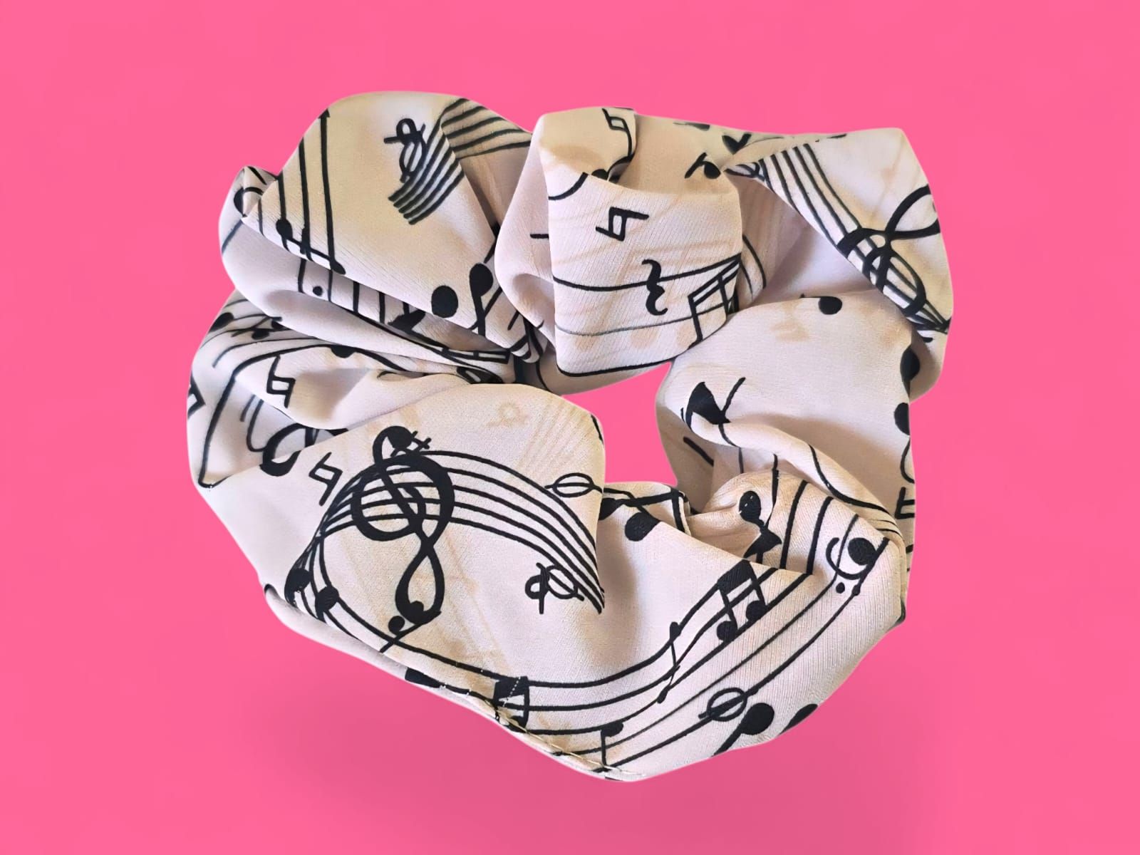 Coletero blanco con notas musicales negras sobre fondo rosa.