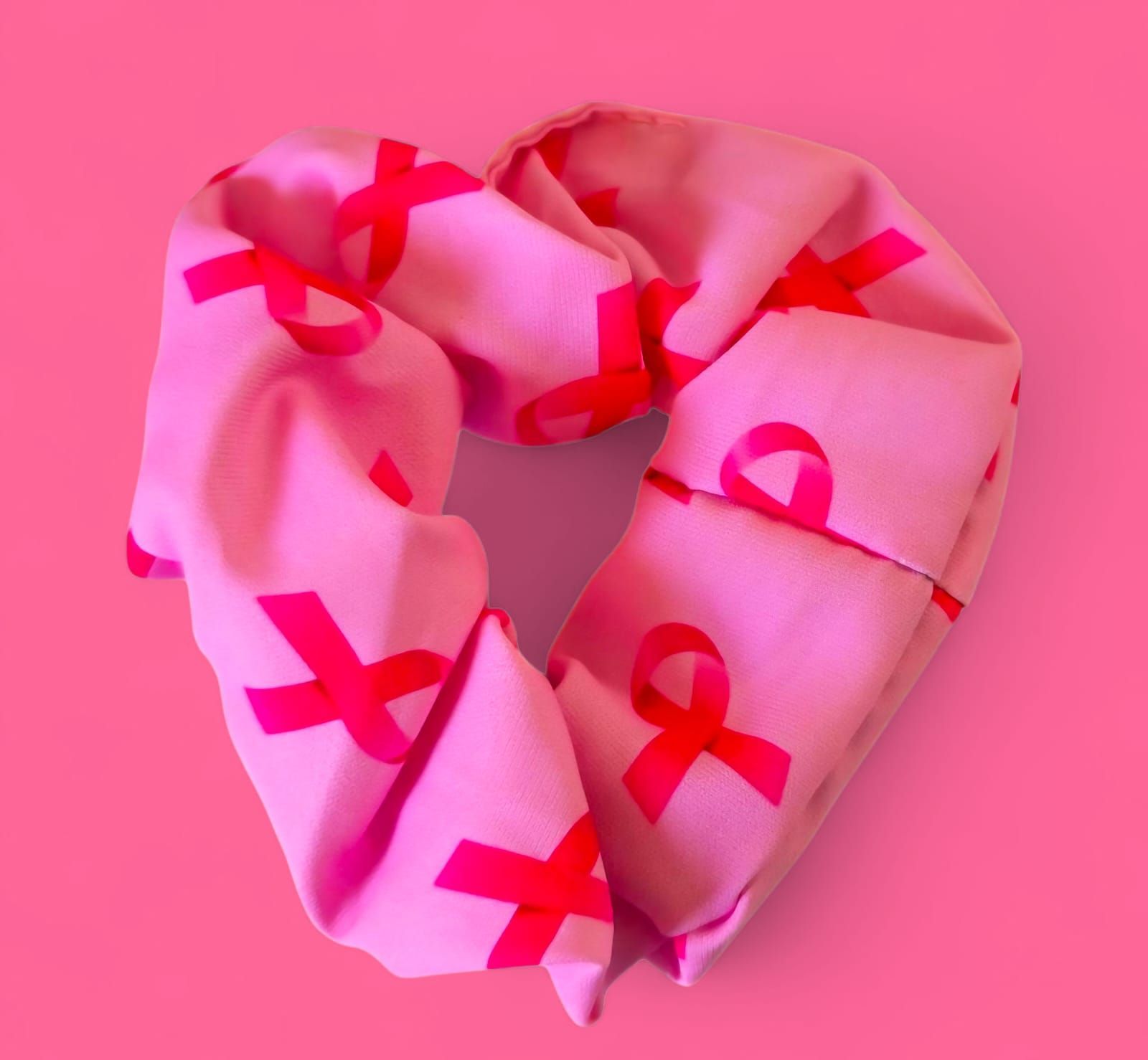 Bufanda rosa, en forma de corazón, con repetidos iconos de cintas de concientización sobre el cáncer de mama de color rosa.