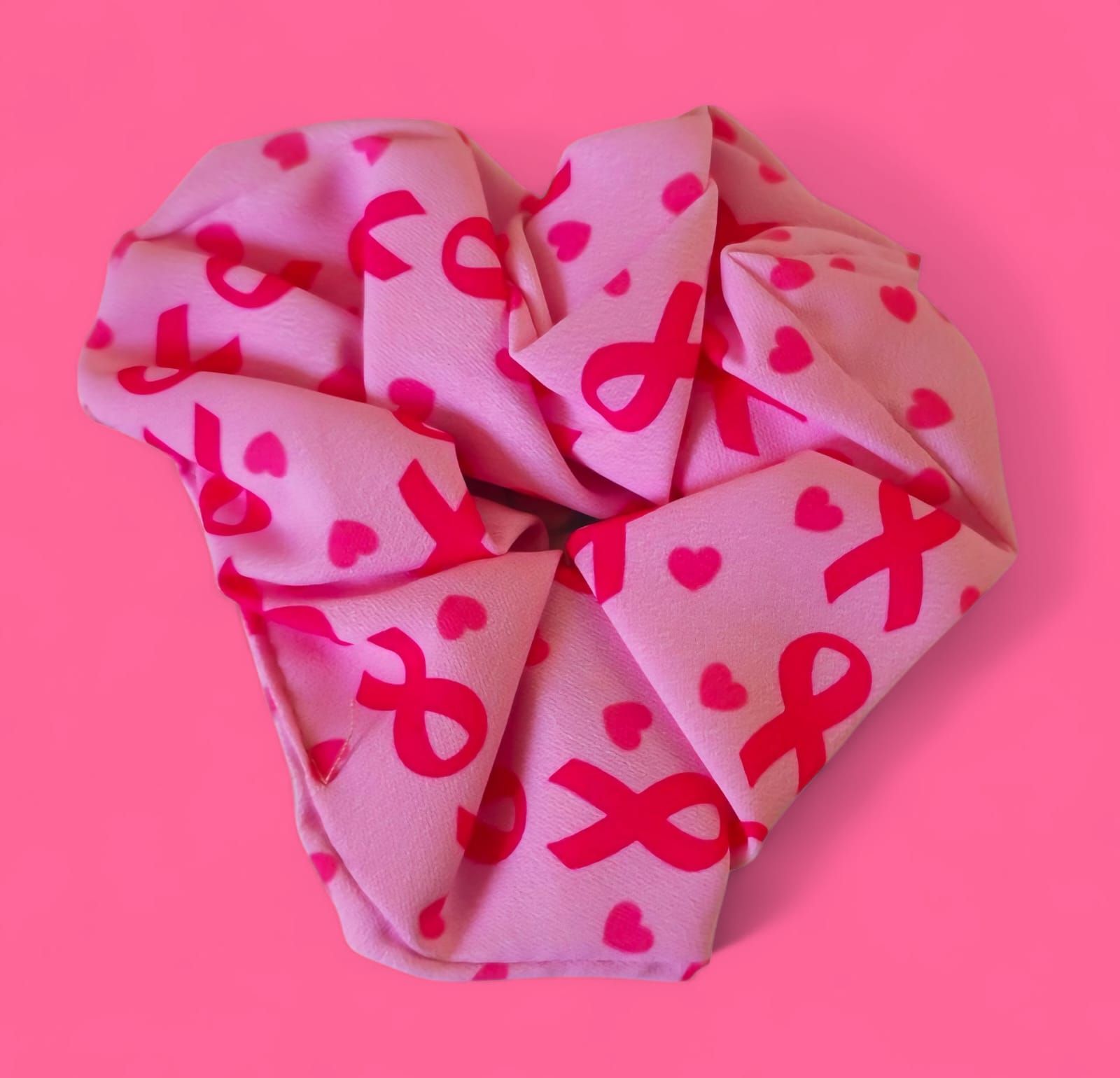 Tela rosa doblada en forma de corazón, con cintas y corazones rosas.