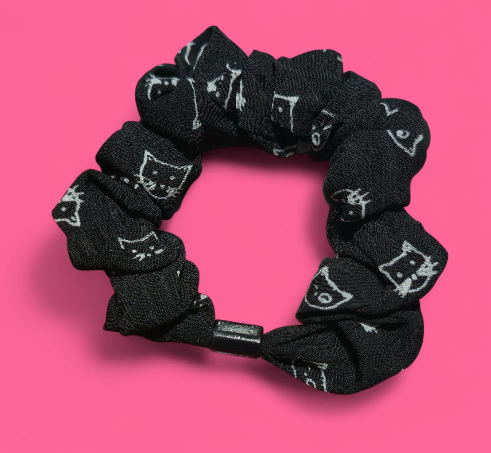 Coletero negro con caras de gato blancas sobre fondo rosa.