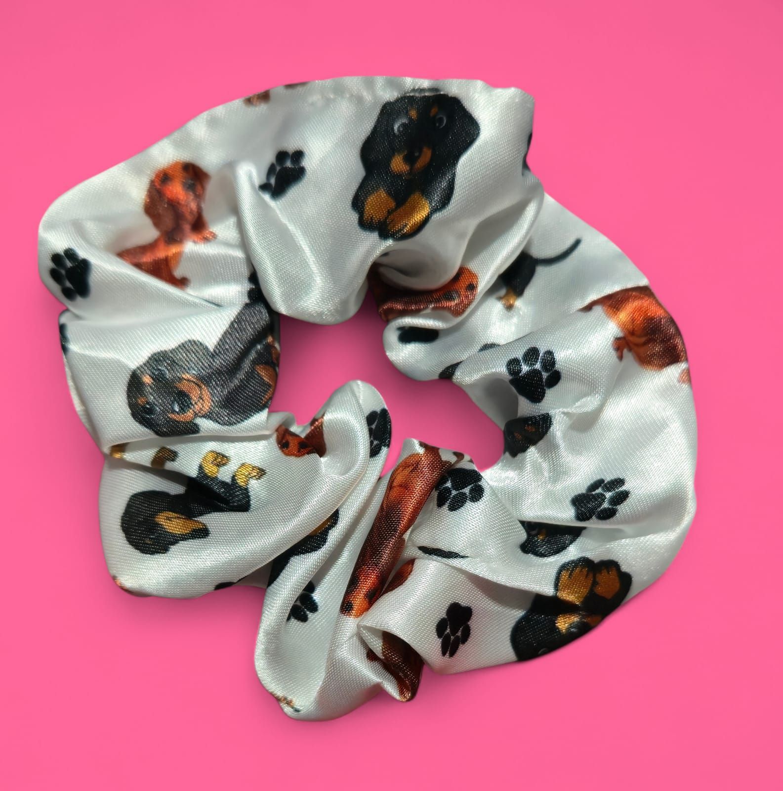 Coletero blanco con estampado de perros salchicha marrones y negros y huellas de patas negras.