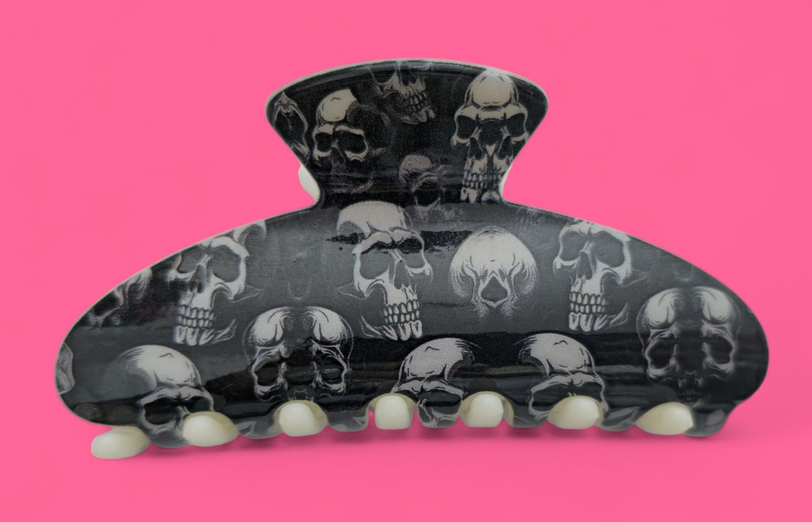 Garra para el cabello con estampado de calavera negra sobre fondo rosa.