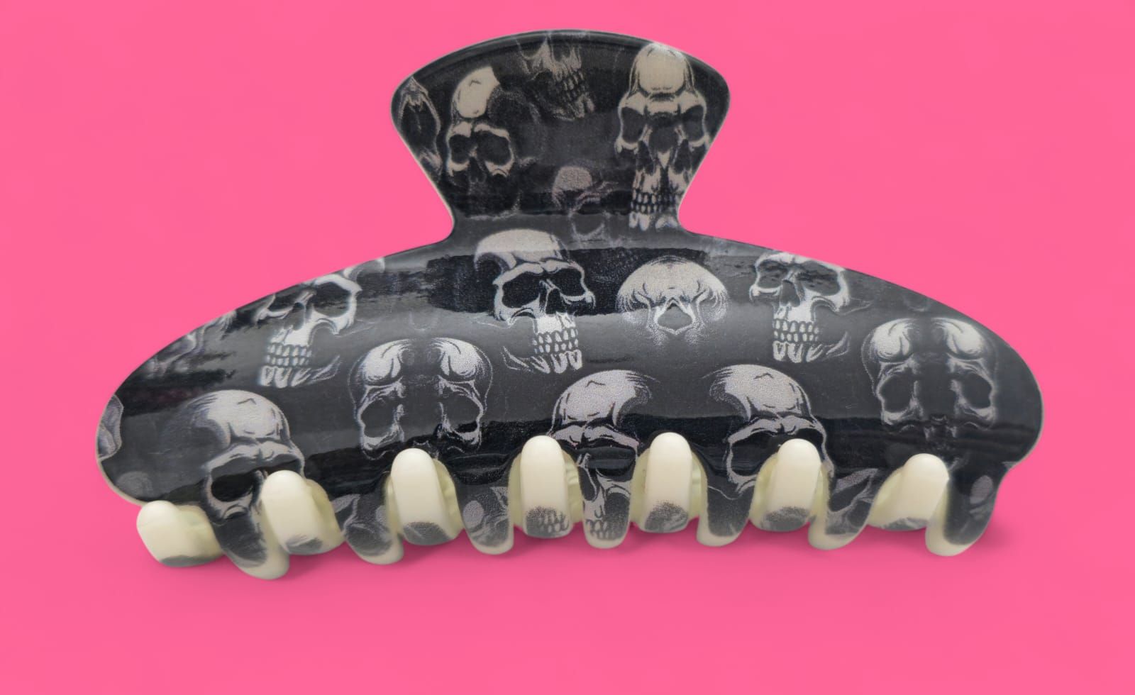Garra para el cabello con estampado de calavera negra sobre fondo rosa.