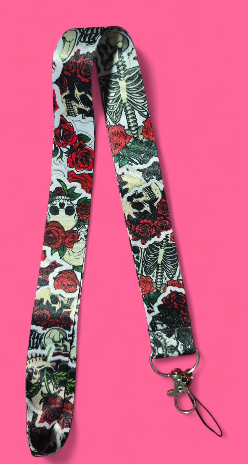 Cordón con fondo blanco, que presenta rosas rojas, calaveras y huesos.