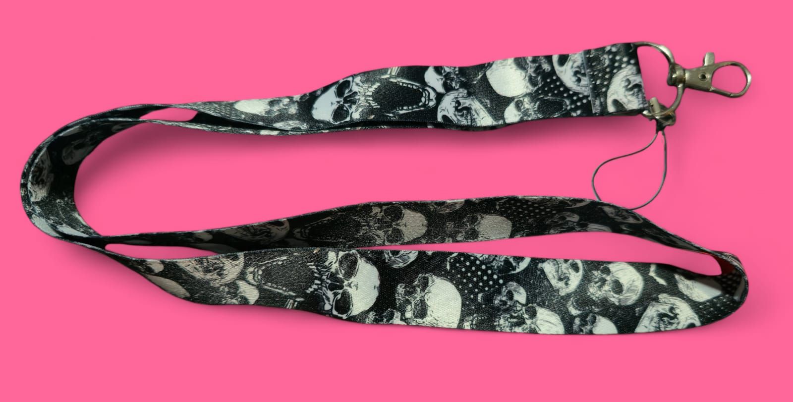 Cordón con estampado de calavera en blanco y negro con cierre plateado sobre un fondo rosa.