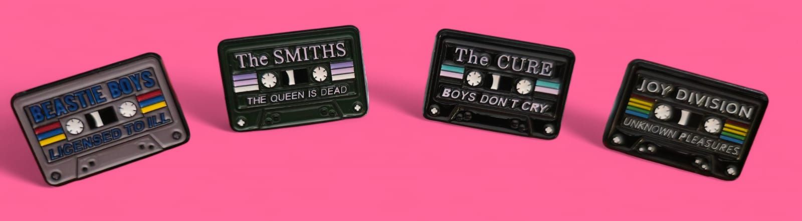 Cintas de casete sobre fondo rosa, etiquetadas como The Smiths, The Cure y Joy Division.