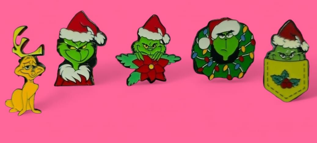 Pines navideños del Grinch, incluyendo a Max, con gorro de Papá Noel, corona y bolsillo. Fondo rosa.