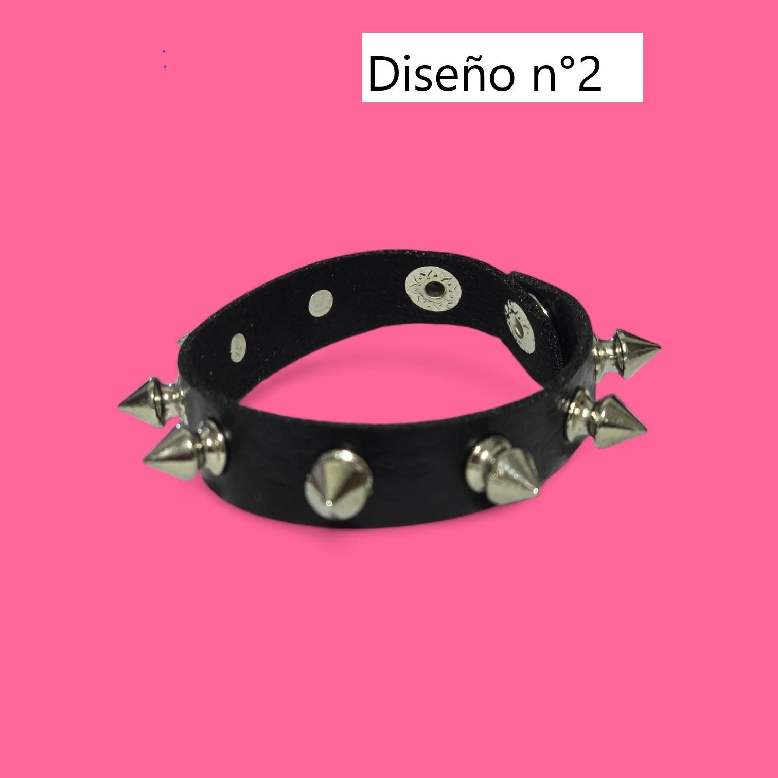 Pulsera con tachuelas negras sobre fondo rosa.