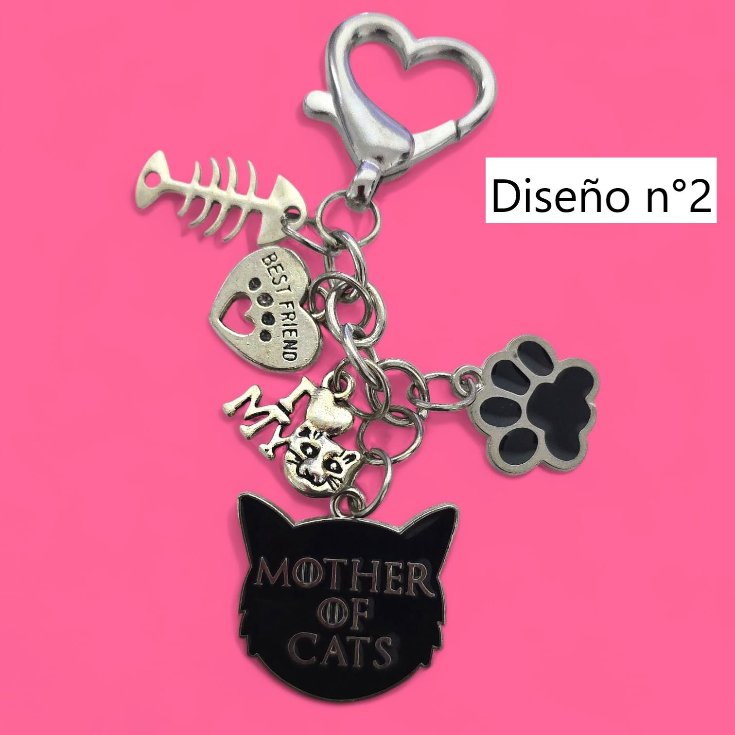 Llavero con forma de gato, con dije de elefante y tres dijes de campana sobre fondo rosa.