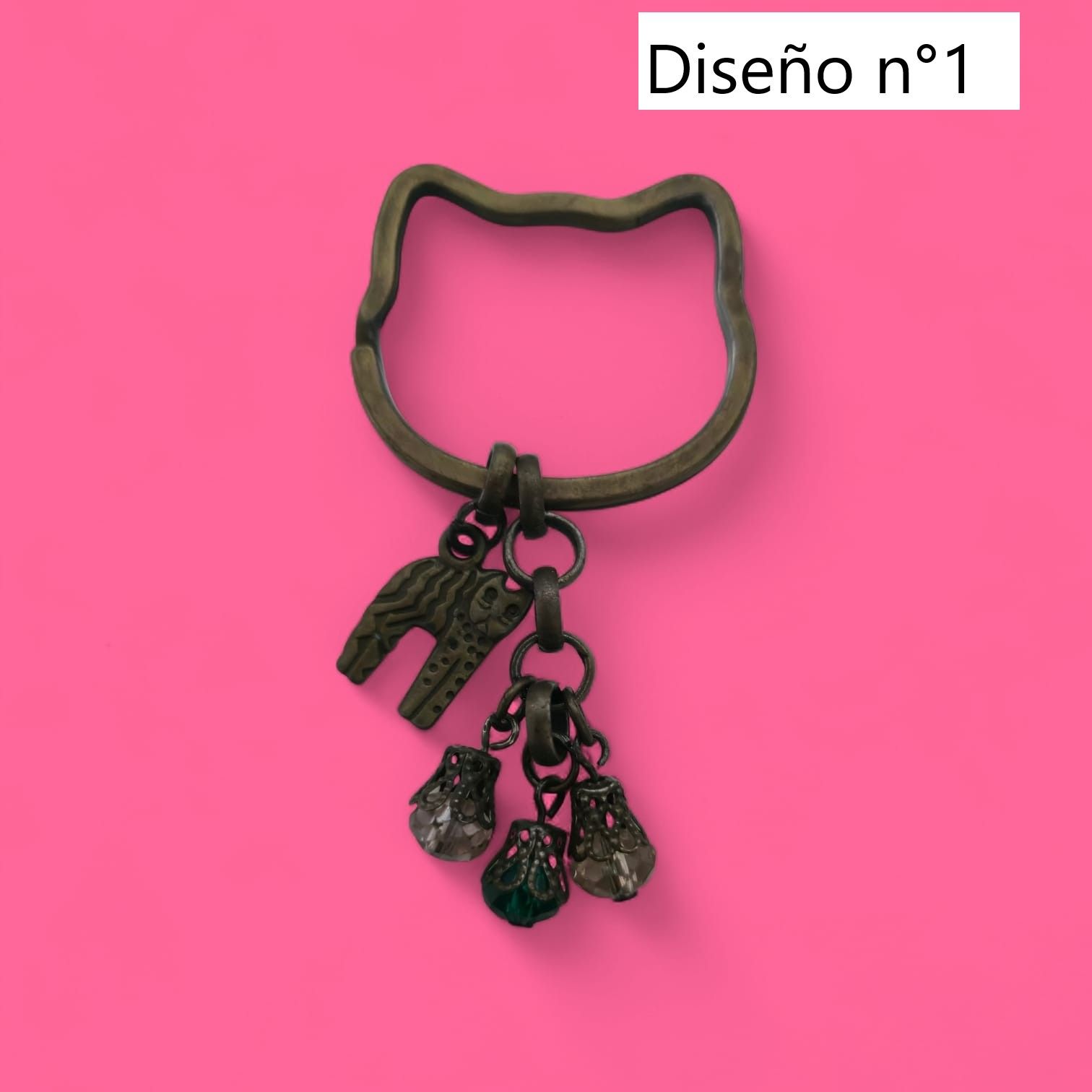 Llavero con forma de gato, con dije de elefante y tres dijes de campana sobre fondo rosa.