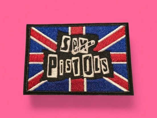 Parche de los Sex Pistols sobre fondo Union Jack, con letras negras y un imperdible.