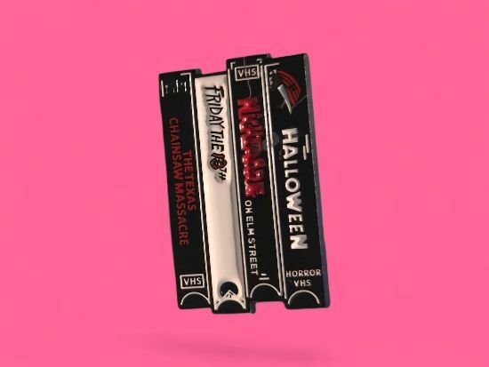 Cintas VHS de películas de terror sobre un fondo rosa: La masacre de Texas, Viernes 13, Pesadilla en Elm Street, Halloween.