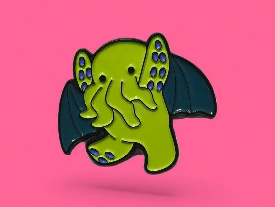 Lindo pin de esmalte verde de Cthulhu con alas azules, sobre un fondo rosa.