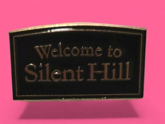 Cartel negro y dorado que dice "Bienvenido a Silent Hill" sobre un fondo rosa.