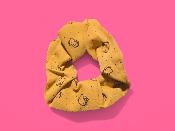 Coletero amarillo de Hello Kitty sobre fondo rosa.