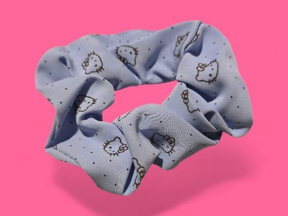 Coletero de Hello Kitty de color azul claro sobre fondo rosa.