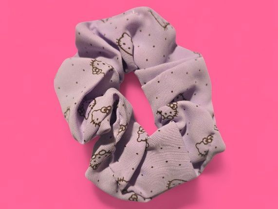 Coletero de Hello Kitty color lavanda sobre fondo rosa.