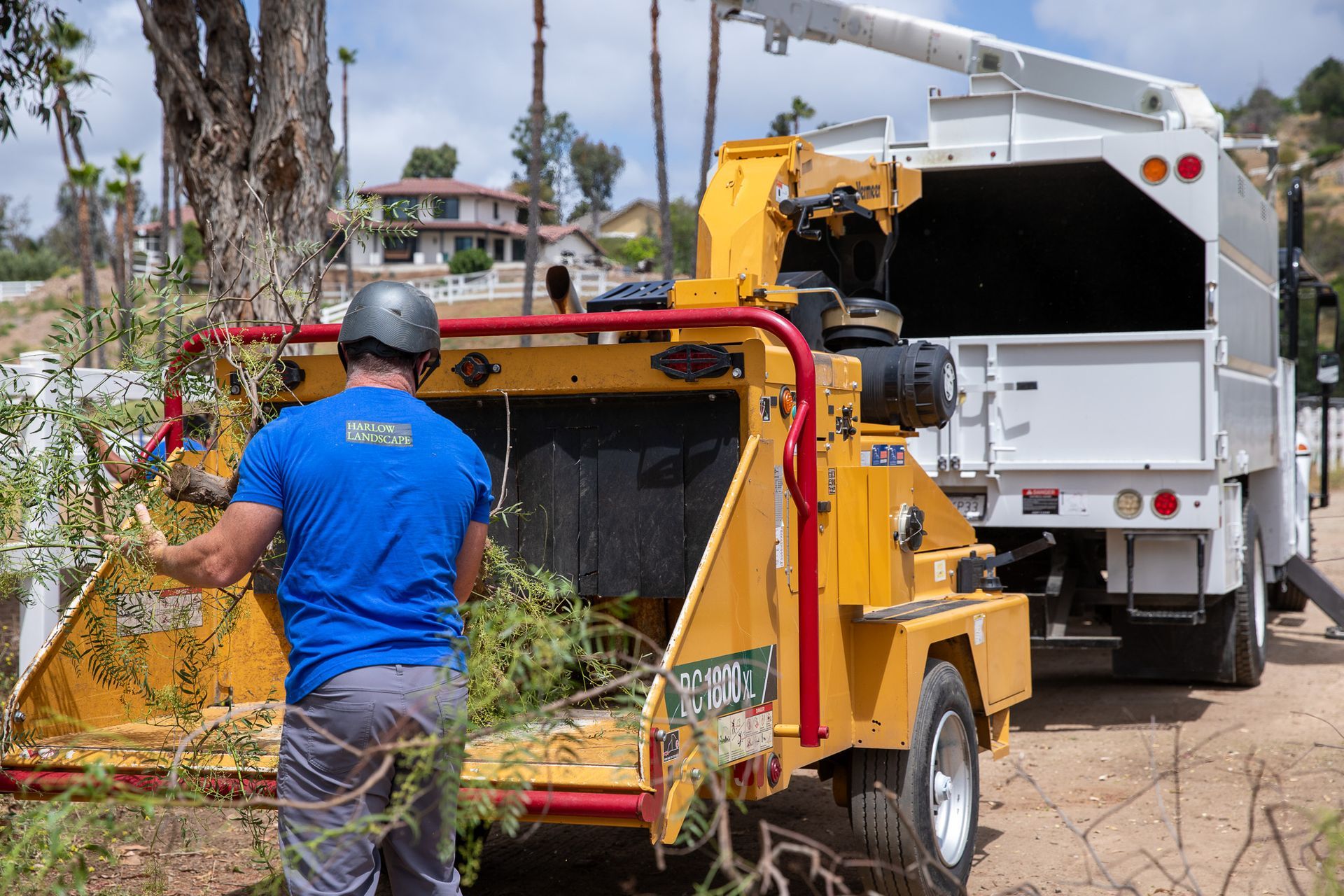 A man is working on a tree chipper next to a truck.
