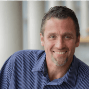 Bill Cox in a blue striped shirt smiling for the camera.