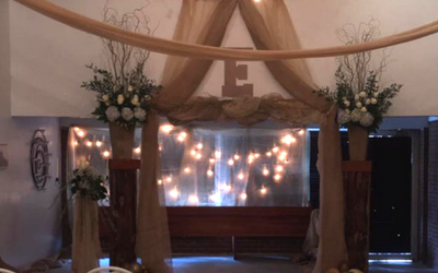 Decorated indoor archway with draped fabric, flowers, and warm string lights