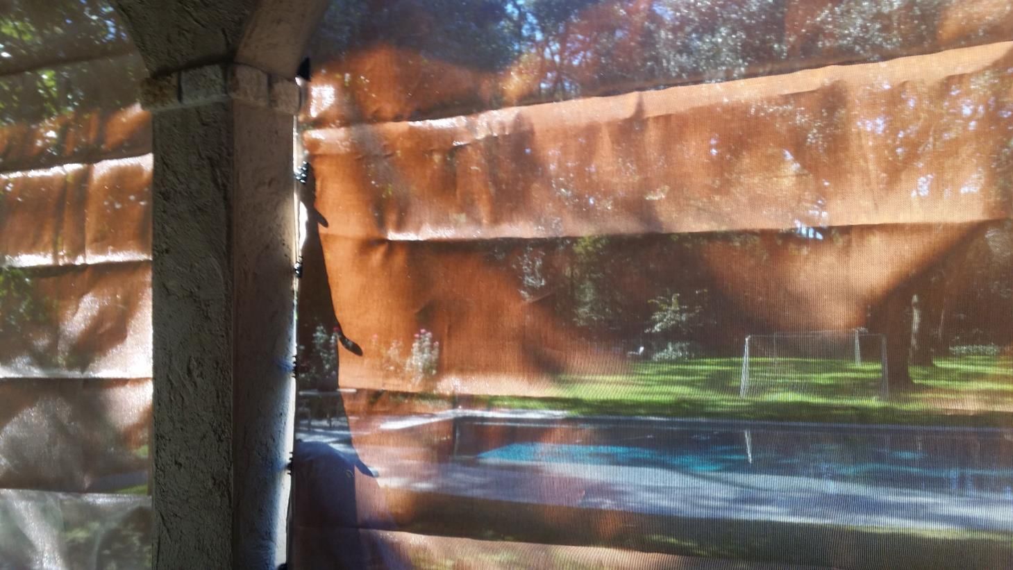 Two windows with green shutters on an orange building.