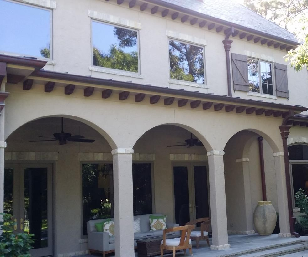 Two windows with green shutters on an orange building.
