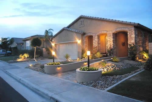 A house with a lot of planters in front of it is lit up at night.
