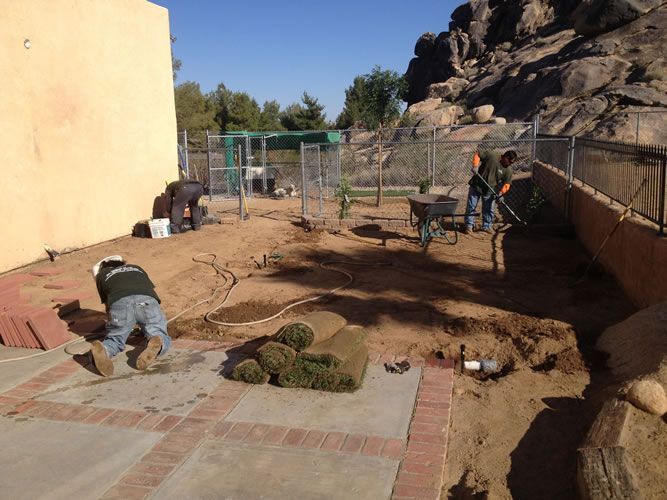 A man is working on a patio with a wheelbarrow.